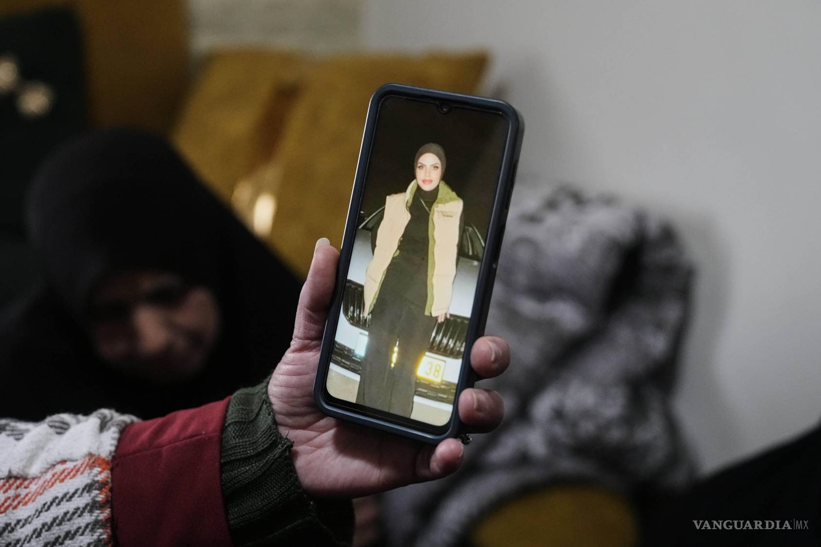 $!Una mujer palestina muestra una foto de Amal Masalmeh, quien murió en un ataque iraní, en la aldea cisjordania de Beit Awa, cerca de Hebrón.