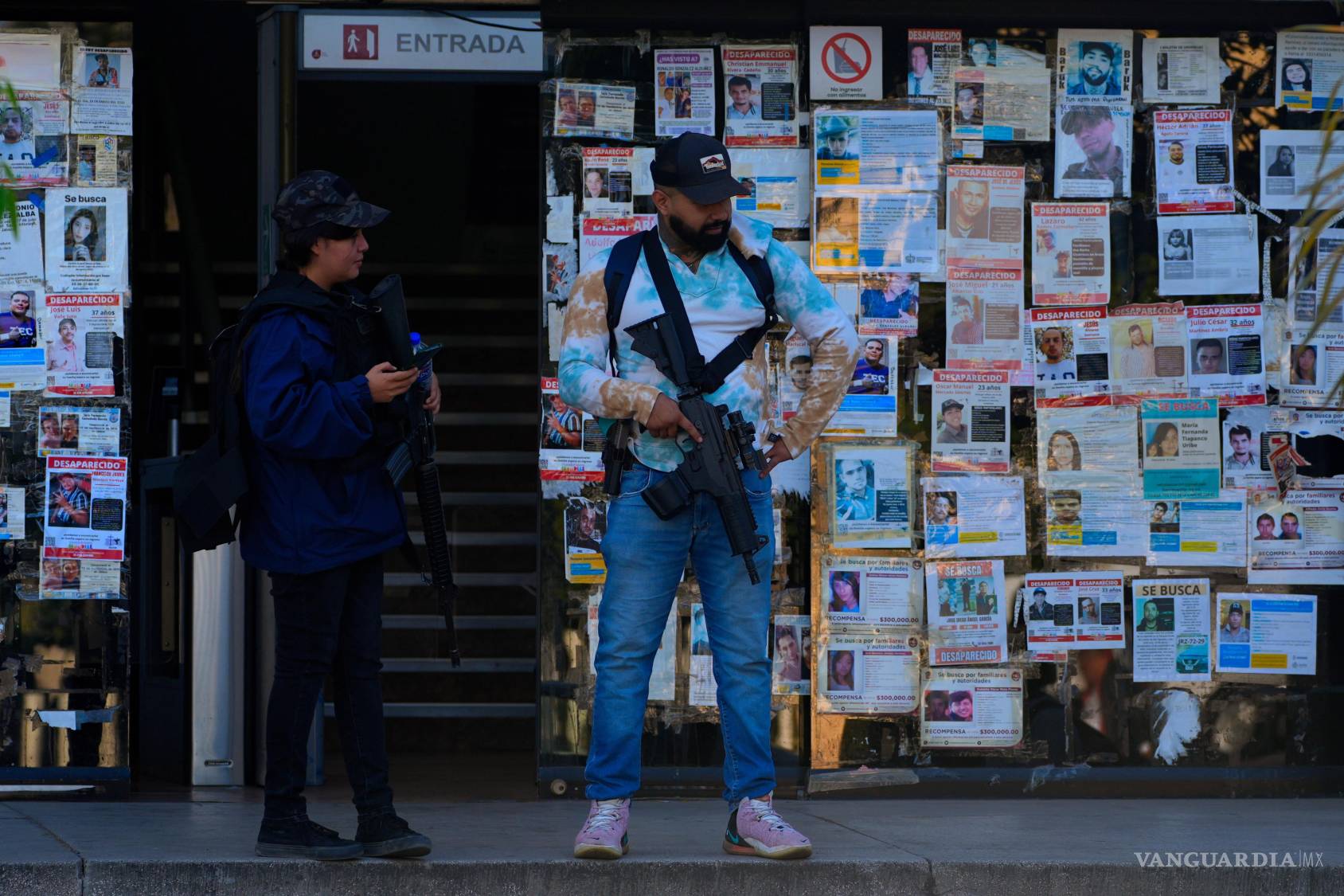 $!Agentes de policía, delante de una pared cubierta con carteles con el rostro de desaparecidos en Guadalajara, Jalisco.