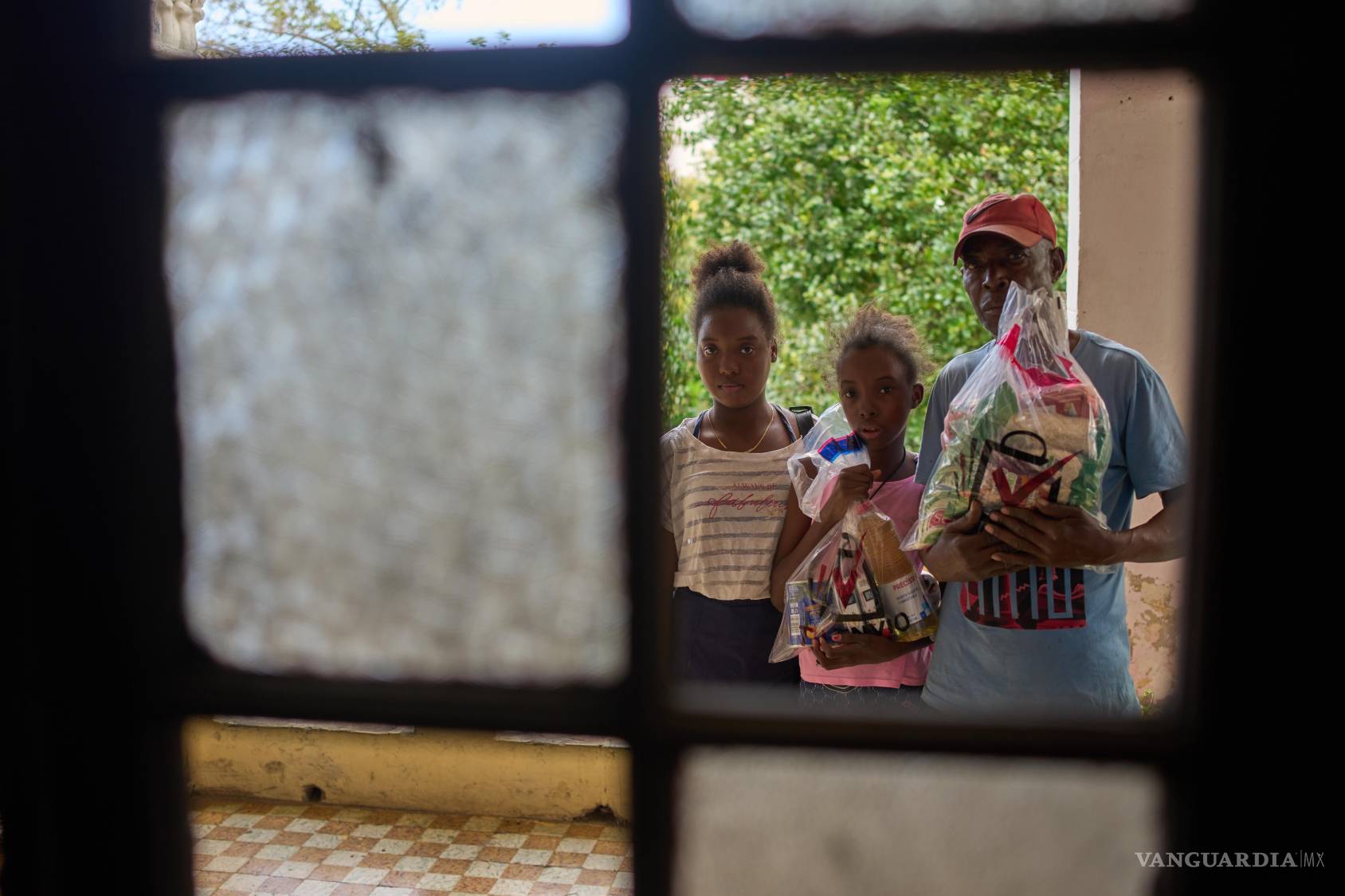 $!Guillermo Beltrán, beneficiario de la ayuda humanitaria mexicana, con sus hijas Chanely y Chanela, sosteniendo los artículos donados en su casa de La Habana.