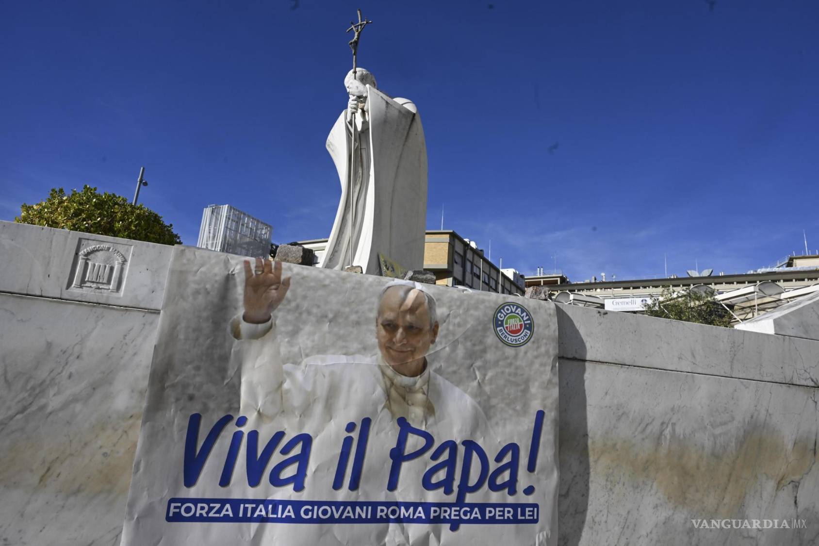$!Un estandarte dedicado al papa León junto a la estatua del papa Juan Pablo II, en el exterior del Hospital Universitario Agostino Gemelli en Roma, Italia.