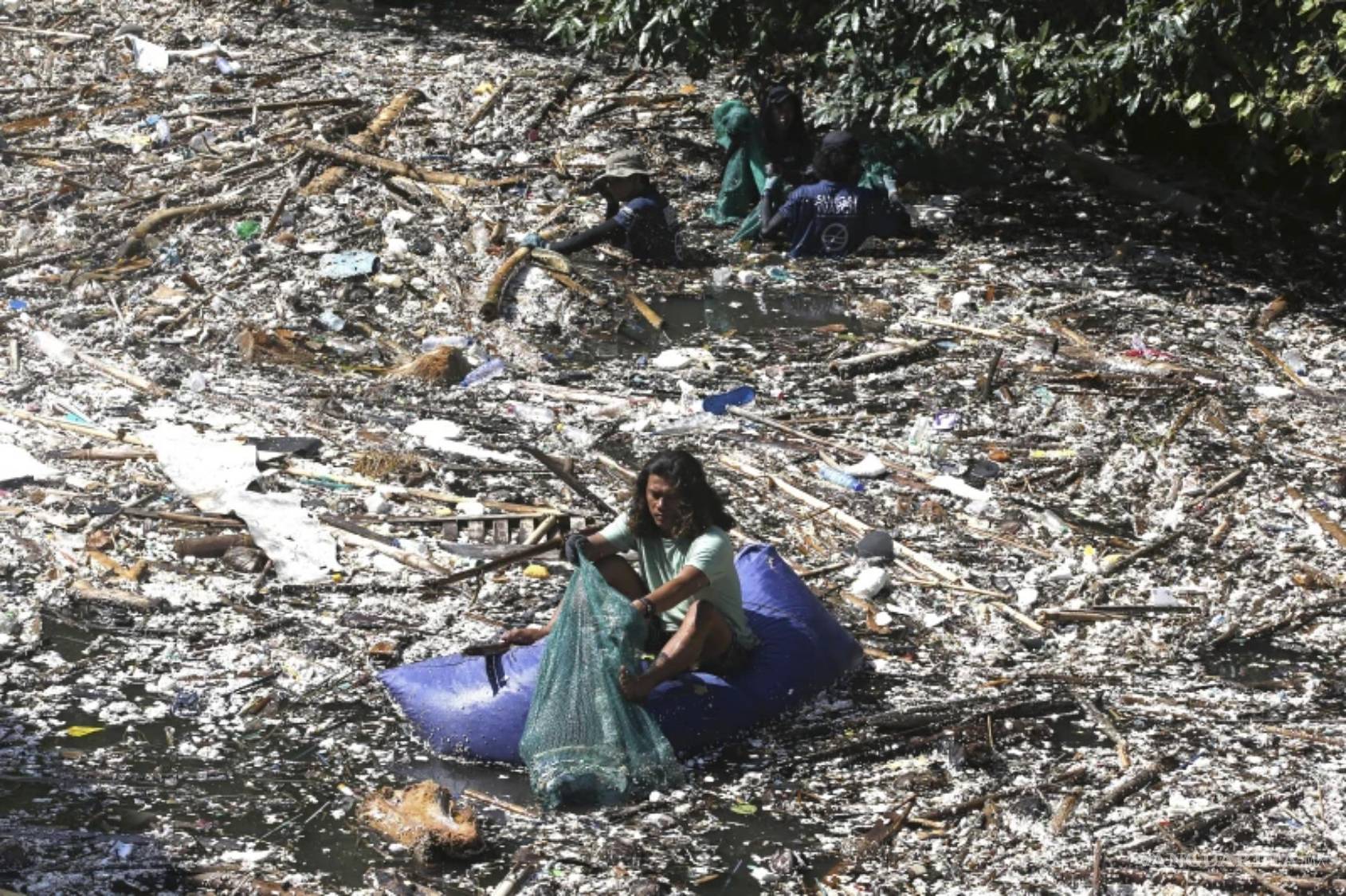 $!Un voluntario recoge basura en un río cubierto de desechos en Pecatu, Bali, Indonesia, el 22 de marzo de 2024.