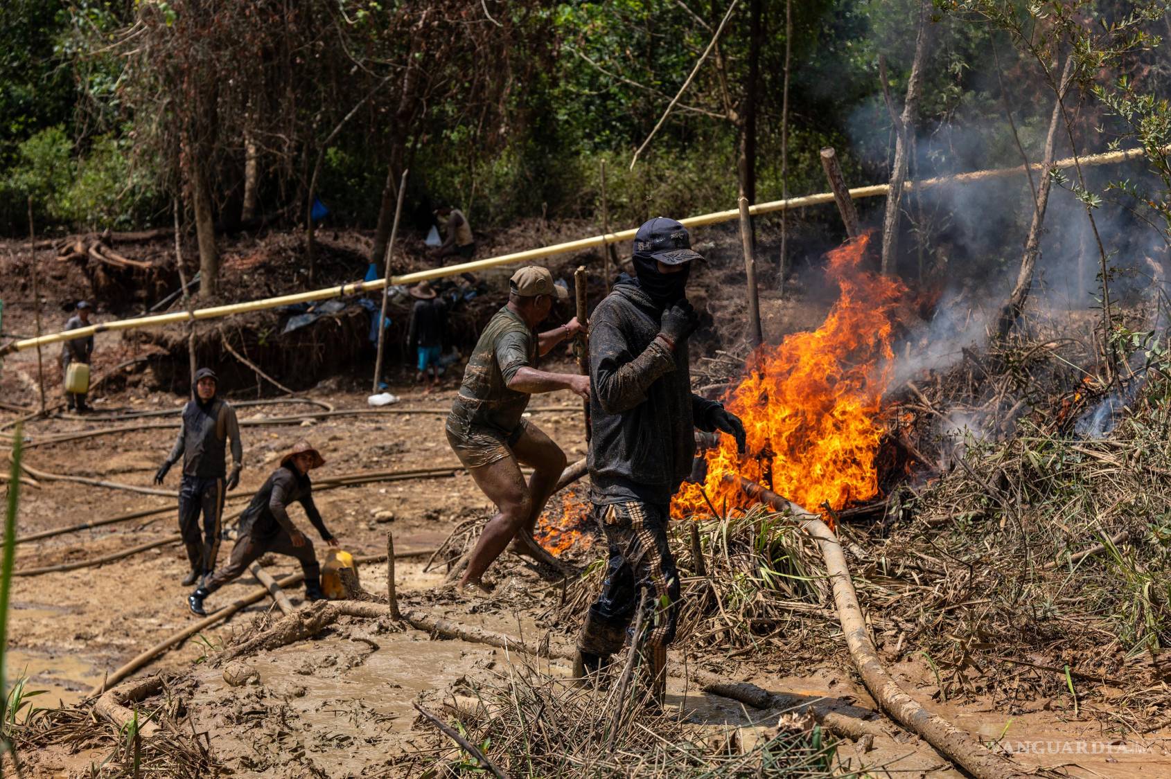 $!Mineros intentan salvar su equipo en llamas después de que soldados le prendieran fuego.