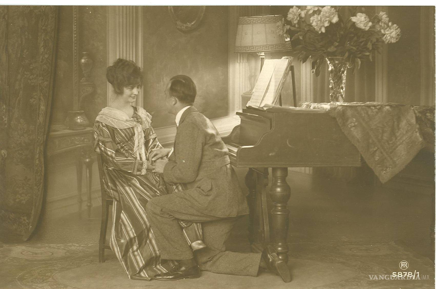 $!La mujer que aparece en esta postal parece ser la misma que la de la imagen anterior. Incluso hay un piano, aunque el diseño es diferente. Destaca un hombre que aparece hincado sobre la pierna derecha. En el reverso, con fecha 25 de octubre de 1920, parte del mensaje dice: “Nenita, ¿Por qué crees que no te extrañé? Si tú eres la única que me consuela y que me anima (...). Dime cuando vienes, pues ya sabes que yo soy muy pesimista, y temo a algunos acontecimientos futuros”.