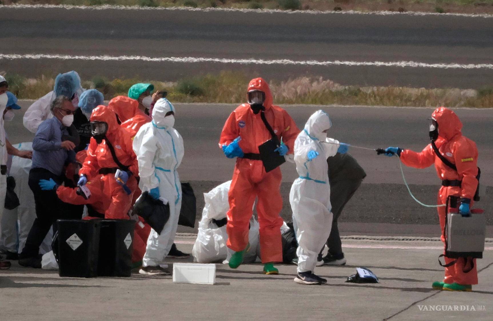 $!Personal de sanidad del gobierno español desinfecta a pasajeros tras desembarcar del crucero afectado por un brote de hantavirus, en el aeropuerto de Tenerife.
