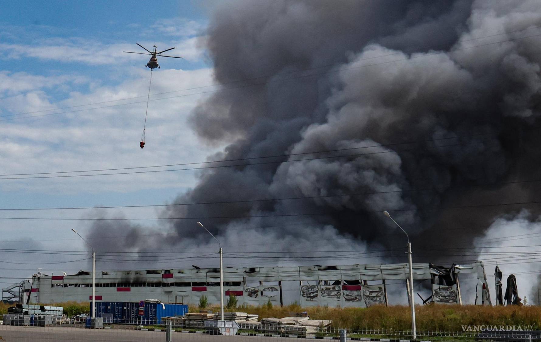 $!Un helicóptero de extinción de incendios sobrevuela una instalación de Wildberries en llamas tras un ataque con drones ucraniano en el parque industrial de Koledino.