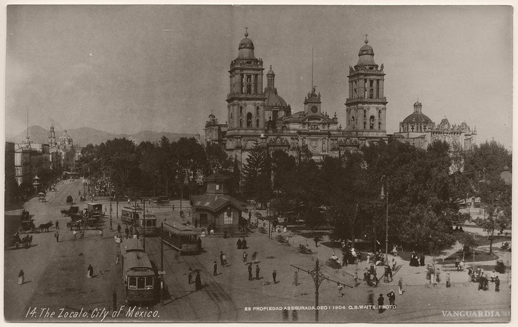 $!En una fotografía de Charles B. Waite, tomada en el Zócalo de la Ciudad de México a principios del siglo XX, los tranvías eléctricos, postes y tendidos aéreos comparten espacio con carruajes y peatones frente a la Catedral Metropolitana. La imagen registra una capital donde distintas tecnologías de transporte coexistían y la electrificación comenzaba a reorganizar el paisaje urbano.