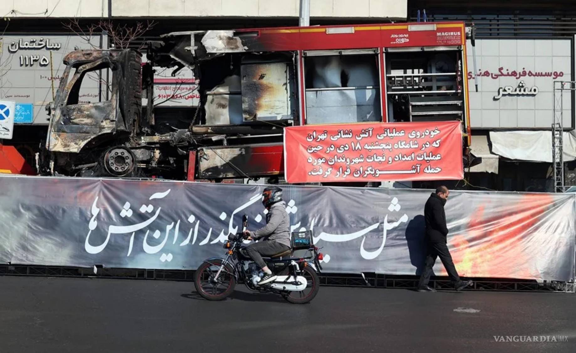 $!Un hombre iraní camina junto a los restos de un vehículo de bomberos que se incendió durante las protestas contra el Gobierno en una calle de Teherán, Irán.