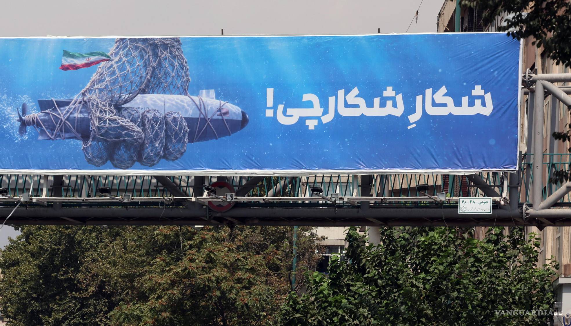 $!Un cartel publicitario de un dron submarino estadounidense capturado por las fuerzas armadas iraníes, junto con una frasea que dice “Cazando al cazador” en Teherán, Irán.