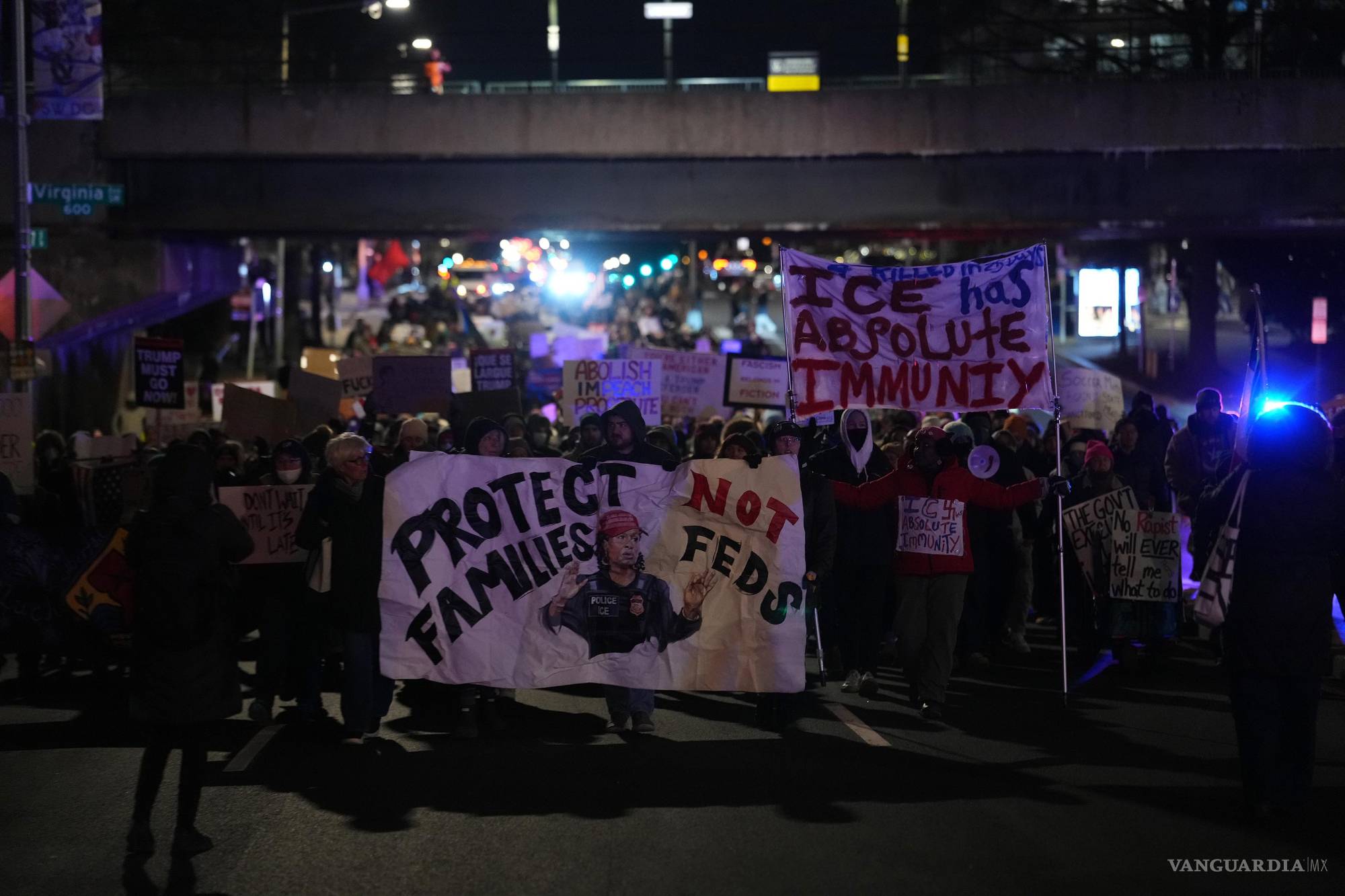$!Manifestantes marchan de noche con pancartas que exigen “Proteger a las familias, no a los federales”, denunciando lo que consideran una inmunidad absoluta de los agentes de inmigración.