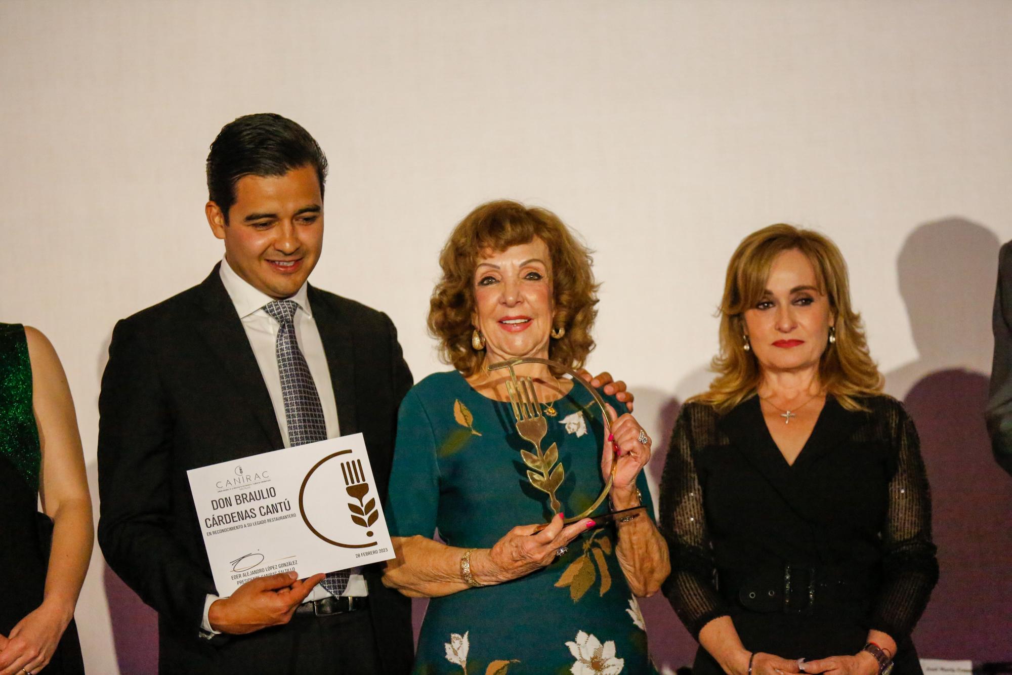 $!Lilia Amparo Cantú de Cárdenas recibió el premio póstumo de manos de Eder López y Azucena Ramos.