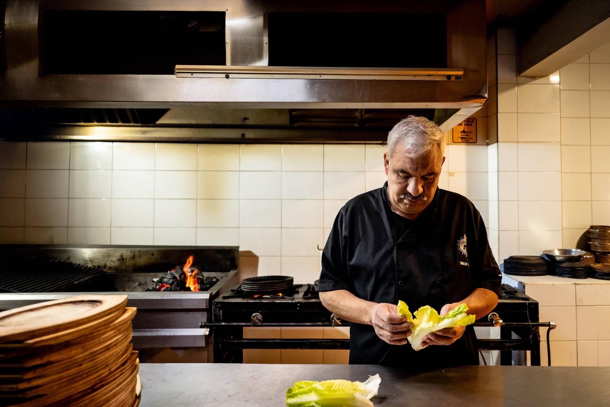 Ubaldo Aguirre trabaja entre brasas y frescura, equilibrando el fuego con la preparación de la ensalada.