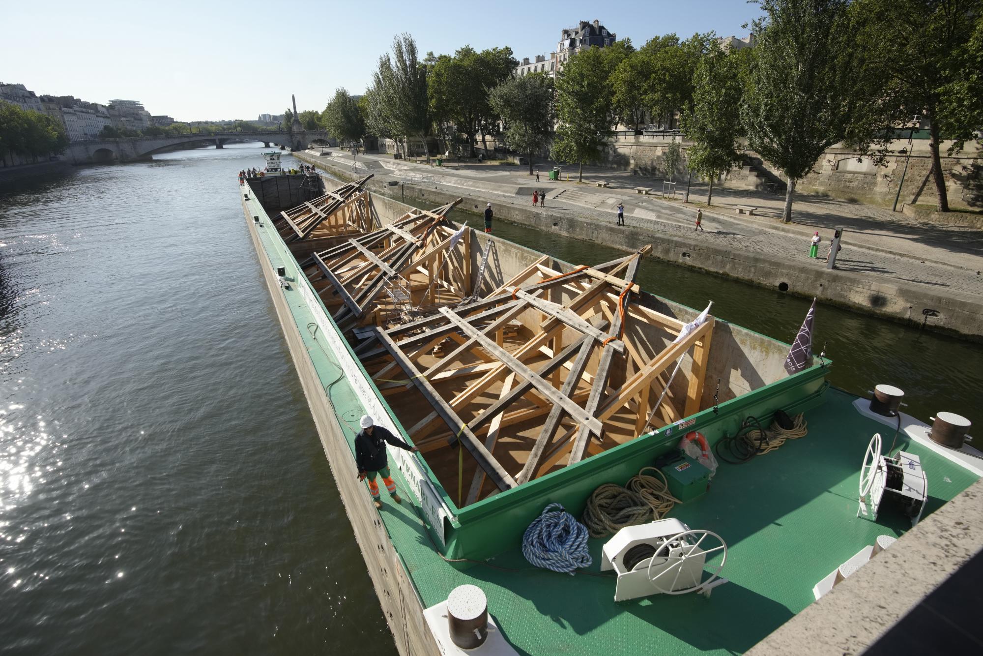 $!Una barcaza cargada con enormes marcos de roble llega cerca de la catedral de Notre Dame de París, el martes 11 de julio de 2023 en París.
