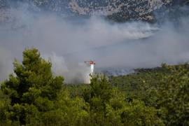 Un helicóptero de bomberos deja caer agua sobre un bosque lleno de humo durante un incendio cerca de Porto Germeno, en el noroeste de Atenas, Grecia.