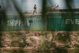 Un miembro de la Guardia Nacional de Texas patrulla el río Bravo, fronterizo con México, desde lo alto de una línea de contenedores de envío en Eagle Pass, Texas.