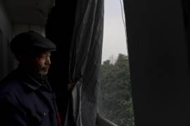 Yang Guoliang retira la cortina utilizada para dar privacidad ante las luces y las cámaras de policía cercanas en su casa de Changzhou, en la provincia oriental china de Jiangsu.