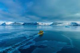 Un barco navega por una bahía con agua congelada a las afueras de Nuuk, Groenlandia.