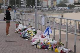 Una mujer para ante un altar improvisado en la playa Bondi el 16 de diciembre de 2026 tras un tiroteo el domingo en Sydney, Australia.