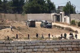 Soldados israelíes hacen guardia junto a colonos frente a viviendas palestinas que estos bloquearon en la localidad de Qusra, al sur de Nablus, en la ocupada Cisjordania, el 12 de agosto de 2026.