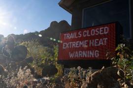 Un letrero avisa que un sendero para excursionistas está cerrado debido al exceso de calor, en la montaña Camelback en Phoenix, Arizona.