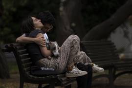 Una pareja disfruta de un momento tranquilo junto con un perro, sentados en un banco en un parque en el centro de Bucarest, Rumania.
