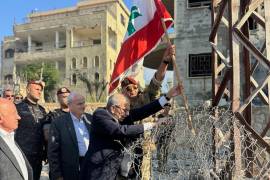 El primer ministro de Líbano, Nawaf Salam (c) iza una bandera libanesa durante una visita al pueblo sureño de Zawtar Al Gharbieh, Líbano.