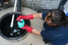 Sonia Estefania Palacios Díaz coloca pastillas de cloro en el tanque donde recogen agua de lluvia en la colonia Iztapalpa en la Ciudad de México.