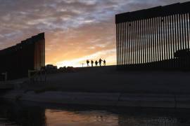 En esta fotografía de archivo del jueves 10 de junio de 2021, un par de familias de inmigrantes brasileños cruzan por una brecha en el muro fronterizo para ingresar a Yuma, Arizona, desde México con el fin de solicitar asilo. AP/Eugene Garcia