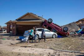 Vecinos pasan ante una casa dañada por el tiempo en Wheatland Drive y Conway Drive en Norman, Oklahoma.