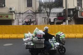 Un repartidor pasa por las barreras establecidas para encerrar a una comunidad en Shanghái, China.