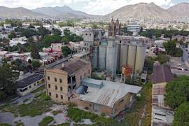 Vista de los deteriorados silos de concreto y la maleza que rodea el antiguo molino, un recordatorio del tiempo y el abandono.