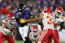 El quarterback de los Ravens Lamar Jackson (8) corre entre cuatro defensores de los Chiefs el 19 de septiembre del 2021 en Baltimore. Con un minuto por jugarse, Jackson convirtió un 4to down espectacular en su propio campo y selló la victoria de Baltimore. (AP Photo/Nick Wass)