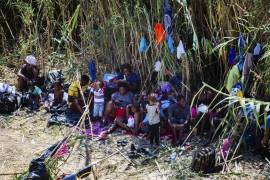 Haitian migrants rest by fresh water plants near the Del Rio International Bridge as part of a group of people from Haiti waiting in Del Rio and Ciudad Acuña to get access to the United States, Friday, Sept. 17, 2021, in Del Rio, Texas. Haitians crossed the Rio Grande freely and in a steady stream, going back and forth between the U.S. and Mexico through knee-deep water with some parents carrying small children on their shoulders. Unable to buy supplies in the U.S., they returned briefly to Mexico for food and cardboard to settle, temporarily at least, under or near the bridge in Del Rio, a city of 35,000 that has been severely strained by migrant flows in recent months. (Marie D. De Jesús/Houston Chronicle via AP)