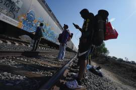 Migrantes miran un tren pasar mientras esperan en las vías con la esperanza de poder abordar uno que vaya hacia el norte, uno que se detenga el tiempo suficiente para que se puedan subir, en Huehuetoca, México.