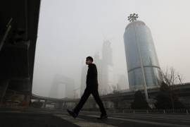 Imagen de 20 de diciembre de 2016, un hombre con una máscara para protegerse contra la contaminación del aire cruza una carretera en Beijing mientras la capital de China está envuelta por una densa niebla tóxica. AP/Andy Wong