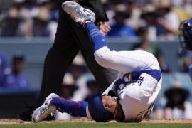 Mookie Betts, de los Dodgers de Los Ángeles se retuerce de dolor sobre el terreno tras ser golpeado por un lanzamiento, durante la séptima entrada del juego ante los Reales de Kansas City.