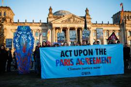 Activistas de Extinction Rebellion protestan con una pancartas que dice ‘Actuar sobre el acuerdo de París’ y un ataúd gigante frente al Parlamento alemán con motivo de los 10 años del Acuerdo de París en Berlín.