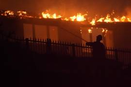 Un bombero trabaja para apagar una estructura en llamas durante un incendio forestal en Laguna Niguel, California.