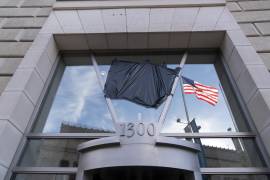 La bandera estadounidense junto a una asta vacía que sostenía la bandera de la Agencia de los Estados Unidos para el Desarrollo Internacional (USAID, por sus siglas en inglés), se refleja en una ventana que mostraba el nombre y el sello de la USAID, fuera de las oficinas de la agencia en Washington. FOTO: