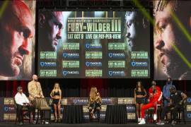 Tyson Fury, de pie a la izquierda, y Deontay Wilder, sentado, de rojo, participan en una conferencia de prensa antes de su pelea por el título de peso pesado, en Las Vegas. AP/Erik Verduzco/Las Vegas Review-Journal