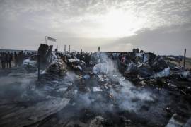Palestinos observan la destrucción causada por el ataque israelí en el campo de desplazados ubicado en Tal al Sultan, en Rafah.