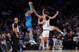 El alero de los Hornets de Charlotte Miles Bridges lanza el balón para encestar un triple mientras lo defienden Quentin Grimes y Jericho Sims de los Knicks de Nueva York.