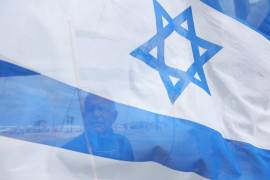Un hombre sostiene la bandera de Israel en Tel Aviv. El país cumple 75 años de su independencia.