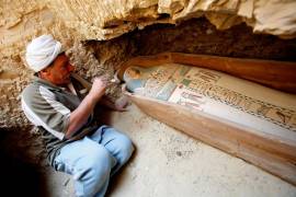 Un arqueólogo egipcio limpia un féretro de madera que contiene una momias cubierta con un trapo de lino, en la pirámide Illahun de la localidad egipcia de Faiyum. EFE/Khaled El-Fiqi