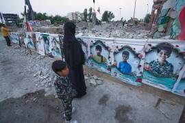 Una mujer y un niño observan los retratos de los niños y maestros fallecidos en un ataque aéreo estadounidense ocurrido el 28 de febrero contra la escuela Shajareh Tayyebeh en Minab, en el sur de Irán, el lunes 7 de septiembre de 2026.