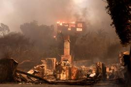 Una casa en llamas y los restos de otra casa quemada en una zona afectada por el incendio forestal de Palisades en Malibú, California. El incendio obligado a la evacuación de al menos 30,000 personas.