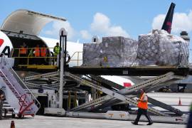 Personas cargan pales con alimentos y kits de higiene en un avión con destino a Cuba organizado por el gobierno de Estados Unidos.