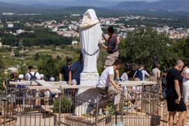 Voluntarios limpian la estatua vandalizada de la Virgen María, que ha sido cubierta con una sábana blanca, en la Colina de las Apariciones en Medjugorje, Bosnia, el 28 de julio de 2026.