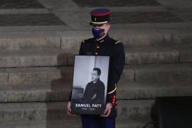 Un guardia republicano sostiene un retrato de Samuel Paty en el patio de la Universidad de la Sorbona durante un evento conmemorativo nacional, el miércoles 21 de octubre de 2020 en París.