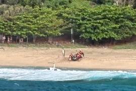 Miembros del equipo de seguridad marítima de Kauai y otras personas brindan ayuda a los heridos tras la caída de un helicóptero turístico de Airborne Aviation en la playa de Kalalau, en Kauai, Hawai.