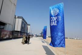 La gente pasa junto al logotipo de la COP28 antes de la Conferencia de las Naciones Unidas sobre el Cambio Climático (COP28) de 2023, en Dubai, Emiratos Árabes Unidos.